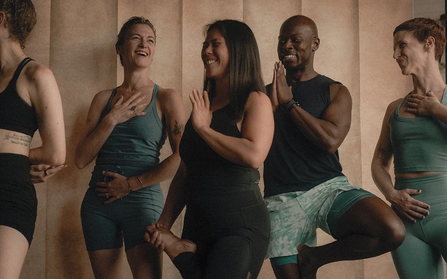 A group of trainees laughing together in tree pose