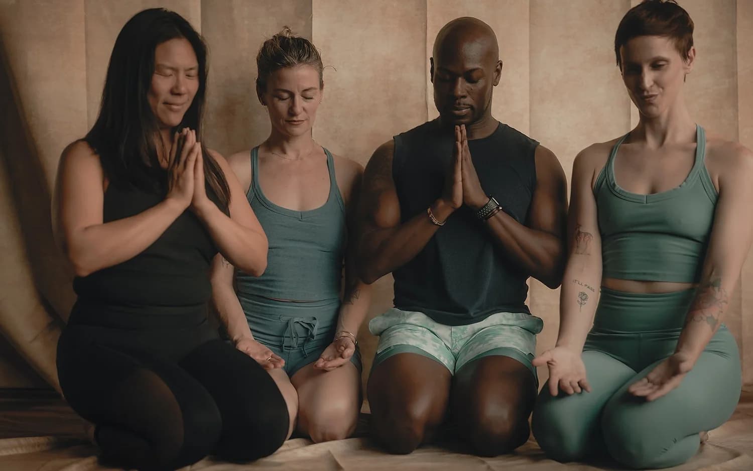 Four trainees kneeling in a row with hands at heart center
